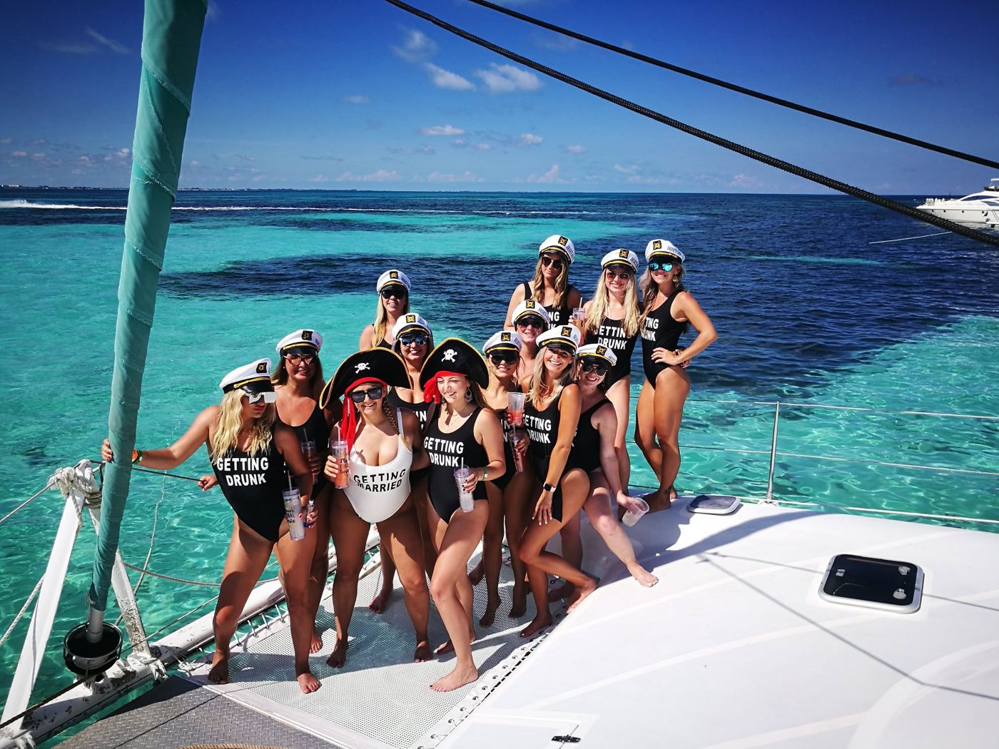 Bachelorette group in captain hats on the catamaran bow