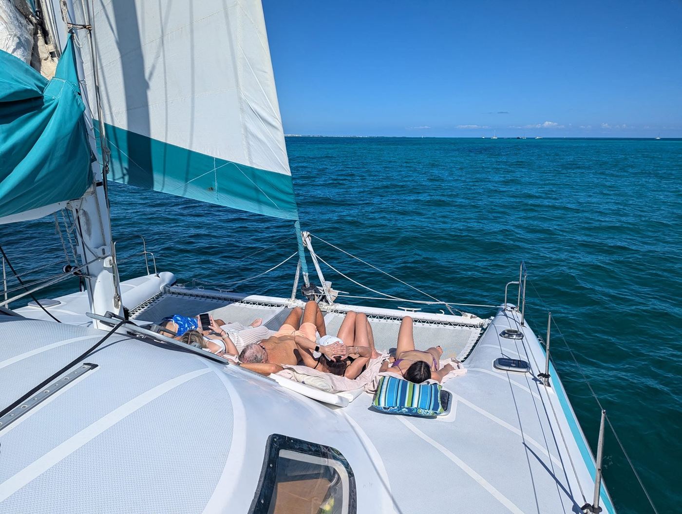 Guests sunbathing on the net with the sail overhead